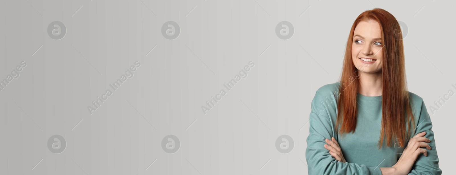 Image of Candid portrait of happy young woman with charming smile and gorgeous red hair on light background, space for text. Horizontal banner design