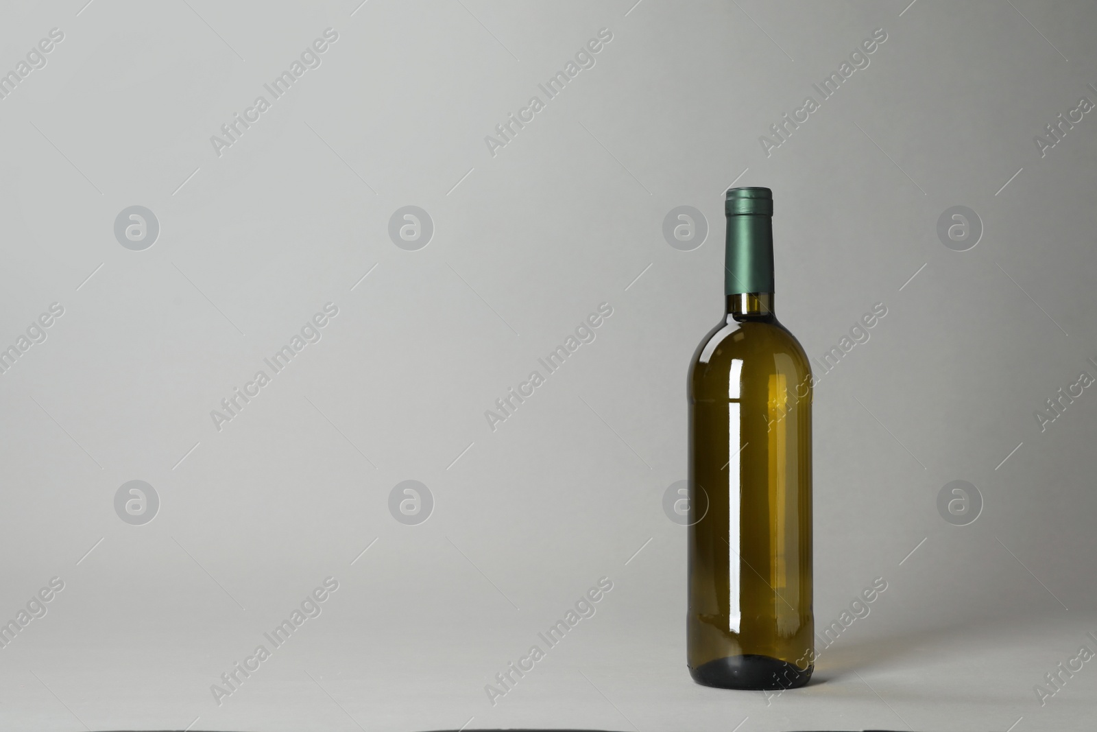 Photo of Bottle of wine on grey background. Space for text