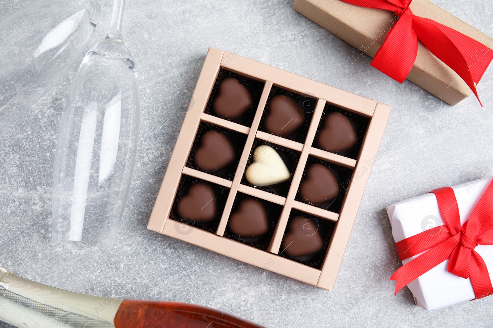 Photo of Flat lay composition with heart shaped chocolate candies on light grey table. Happy Valentine's day