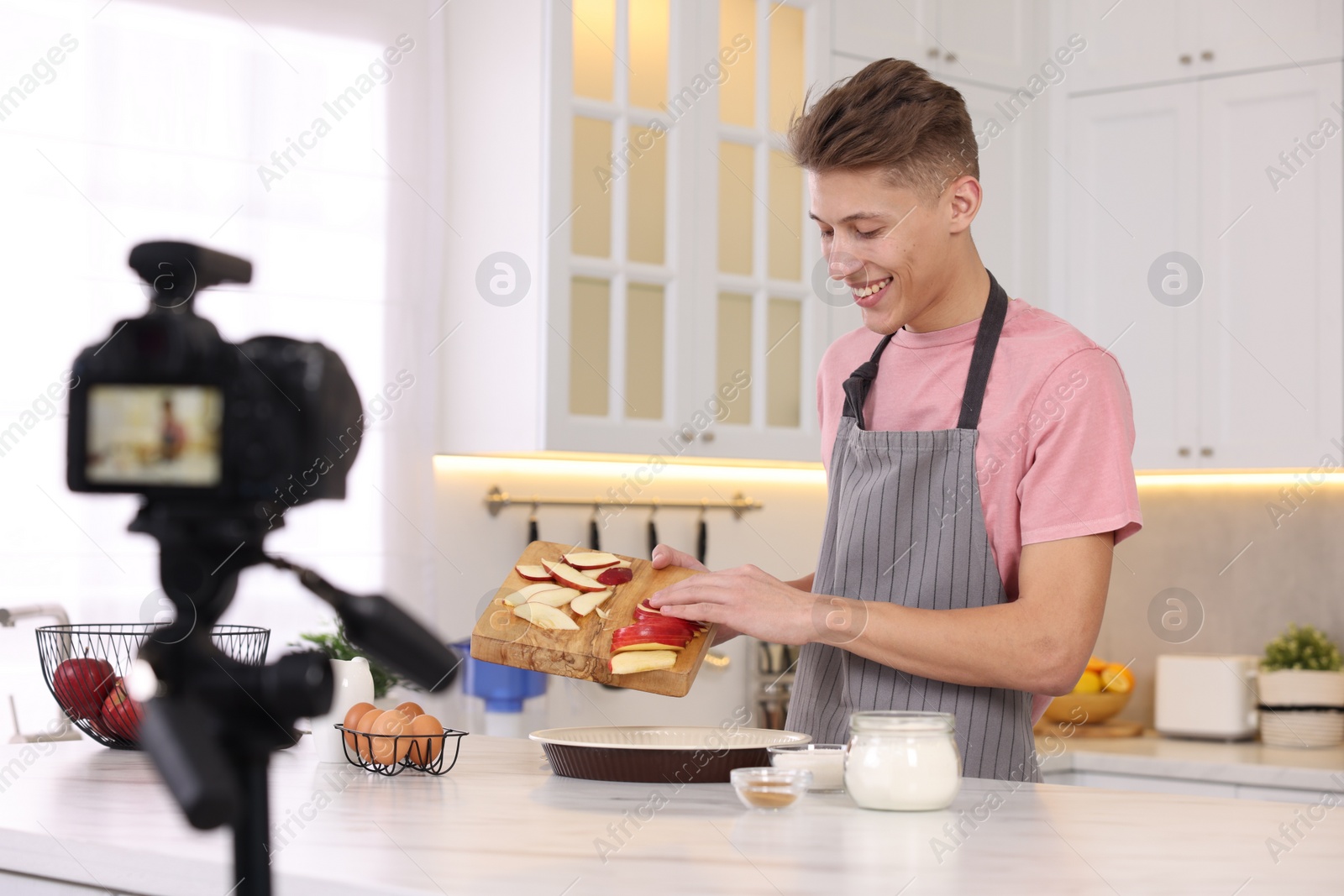 Photo of Smiling food blogger cooking while recording video in kitchen