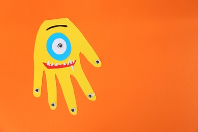 Funny yellow hand shaped monster on orange background, top view with space for text. Halloween decoration