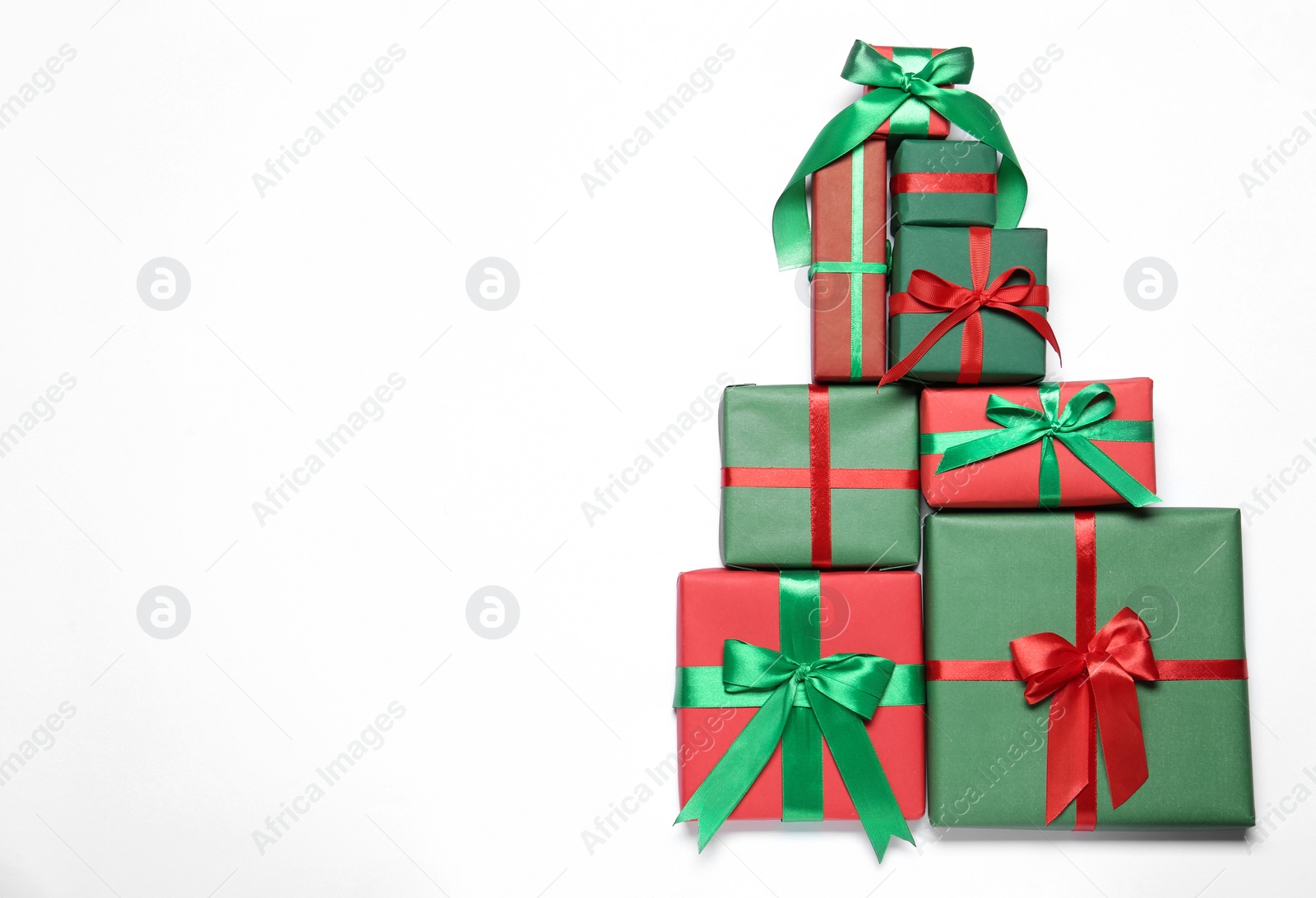 Photo of Christmas tree shape of gift boxes on white background, flat lay. Space for text