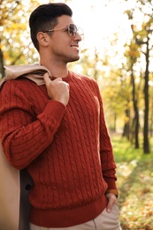 Handsome man walking in park on autumn day