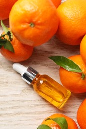 Bottle of tangerine essential oil and fresh fruits on white wooden table, flat lay