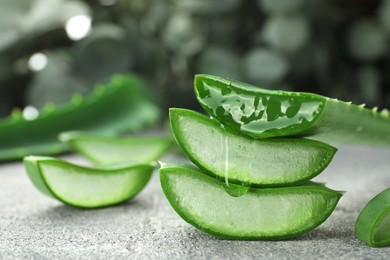 Photo of Fresh aloe vera pieces on grey table, closeup. Space for text