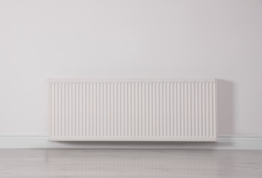Photo of Modern radiator on white wall. Central heating system