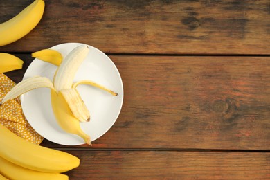 Many delicious ripe bananas on wooden table, flat lay. Space for text