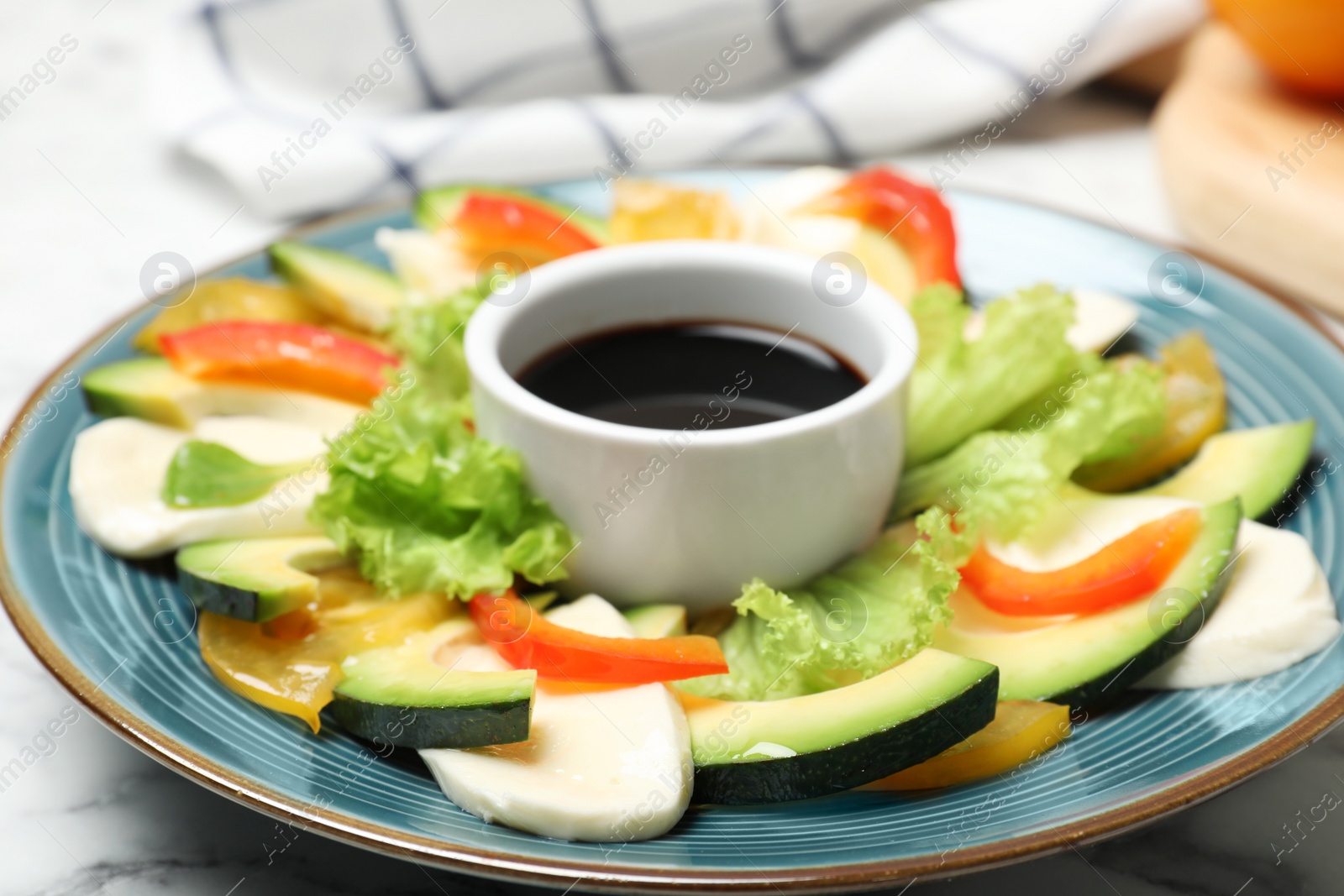 Photo of Plate with fresh salad and balsamic vinegar in bowl on table, closeup