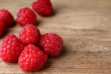 Photo of Heap of tasty ripe raspberries on wooden table, closeup. Space for text