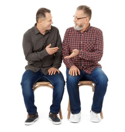 Happy senior men sitting on chairs against white background