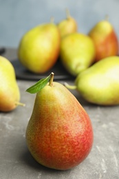 Photo of Ripe juicy pears on grey stone table against blue background
