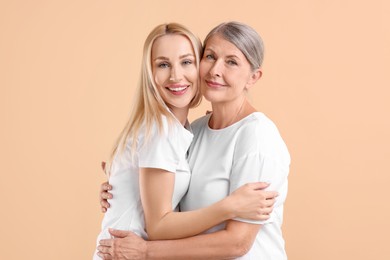 Photo of Family portrait of young woman and her mother on beige background