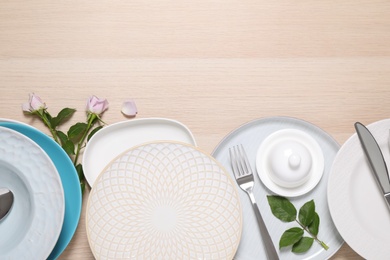 Flat lay composition with beautiful dishware and flowers on wooden table. Space for text