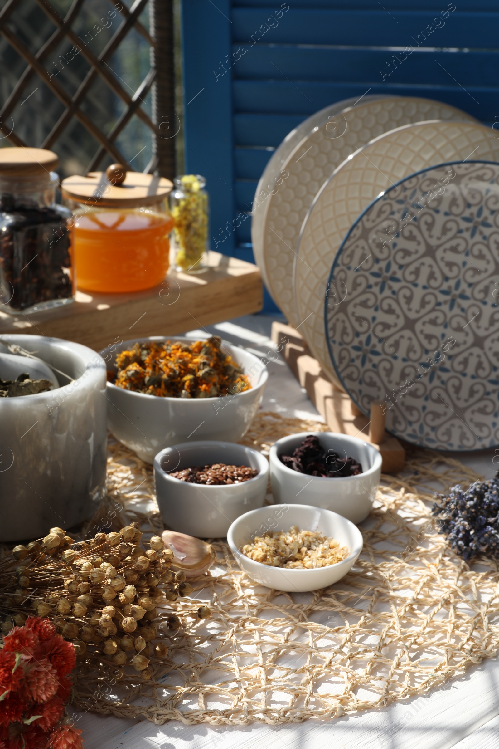 Photo of Many different dry herbs, flowers and plates on white table