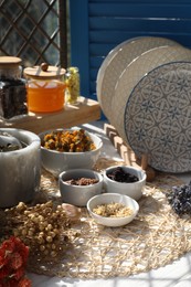 Photo of Many different dry herbs, flowers and plates on white table