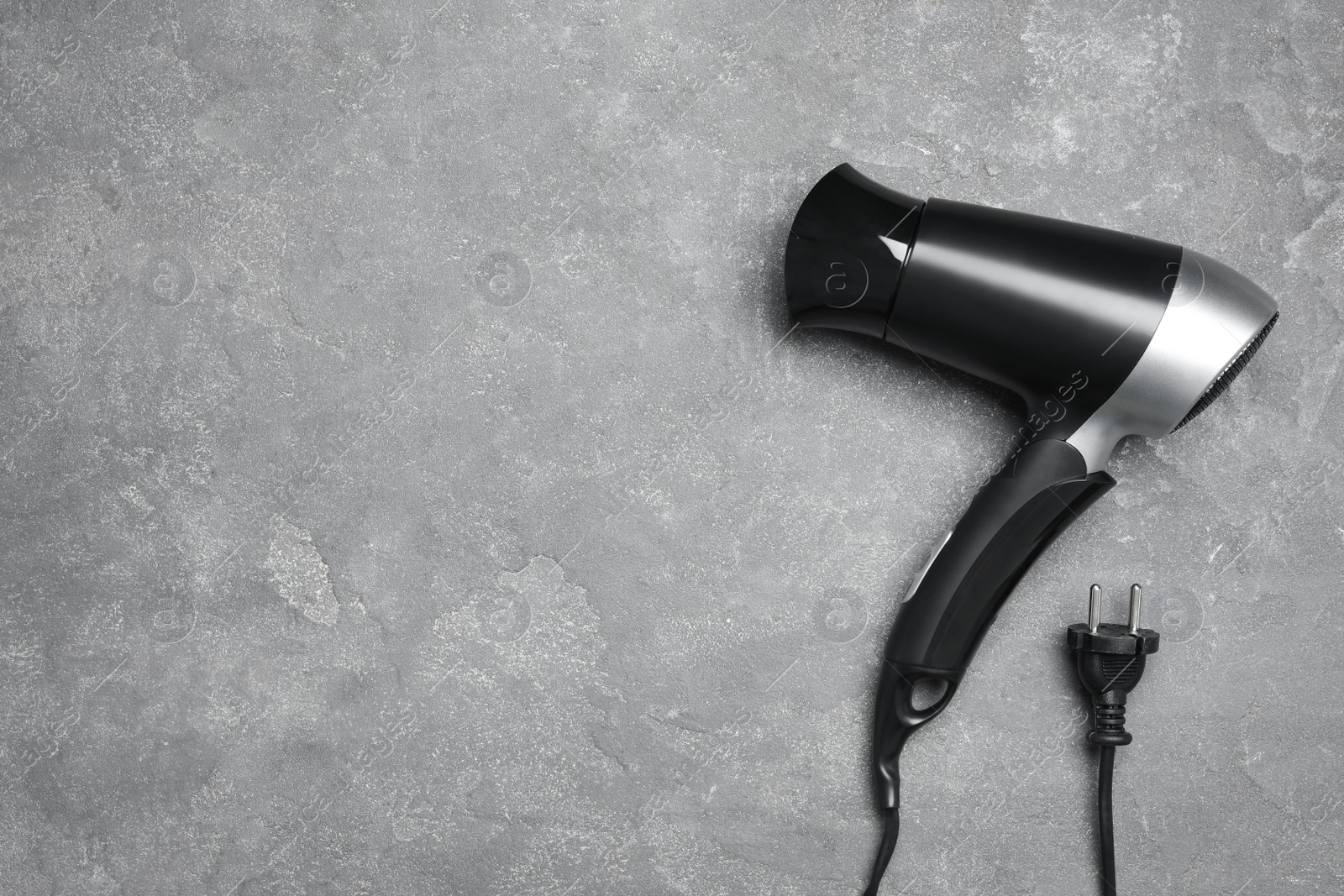 Photo of Hair dryer and space for text on grey marble table, top view. Professional hairdresser tool