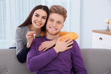 Photo of Young couple with key from their new house indoors. Moving day