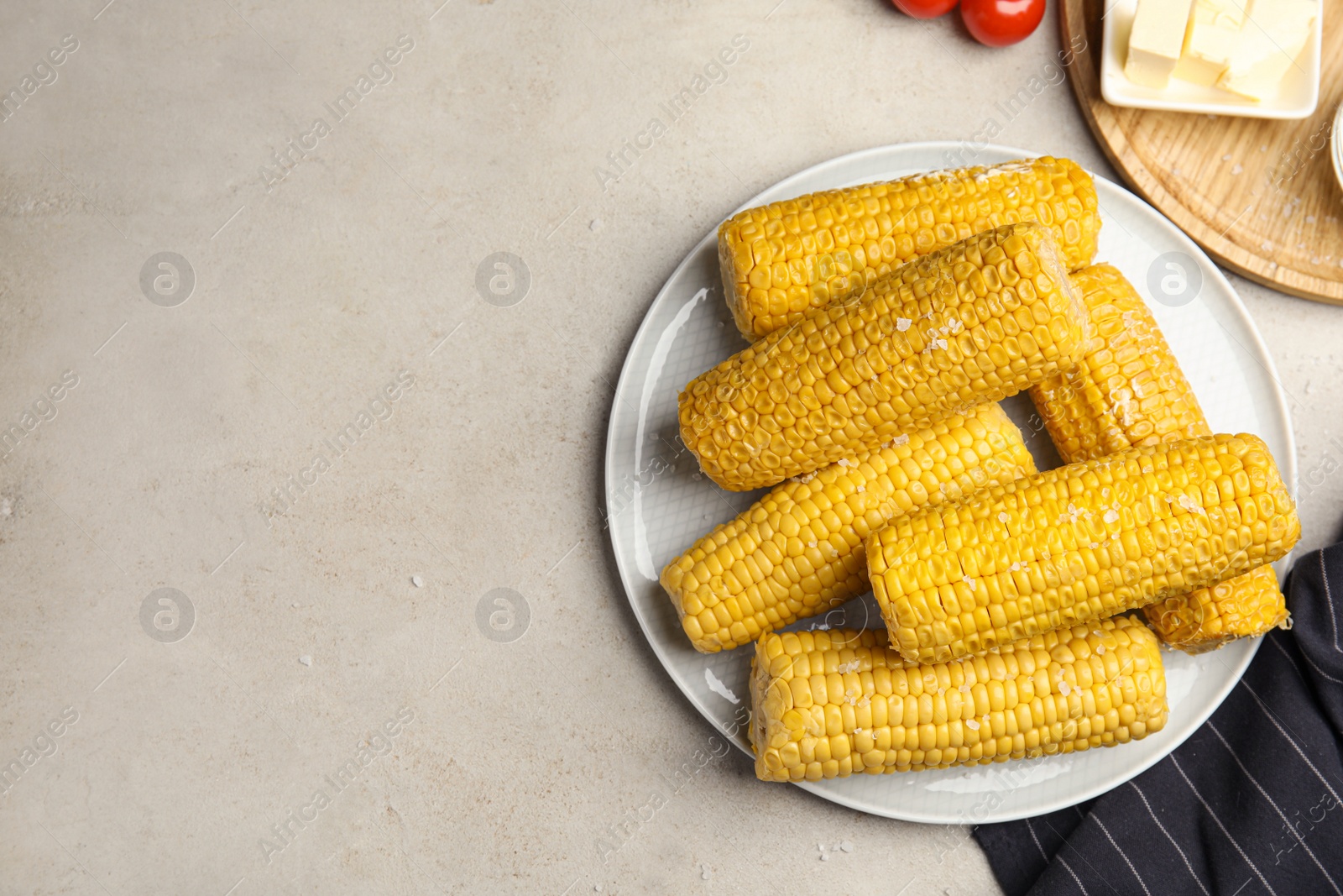Photo of Delicious boiled corn served on light grey table, flat lay. Space for text