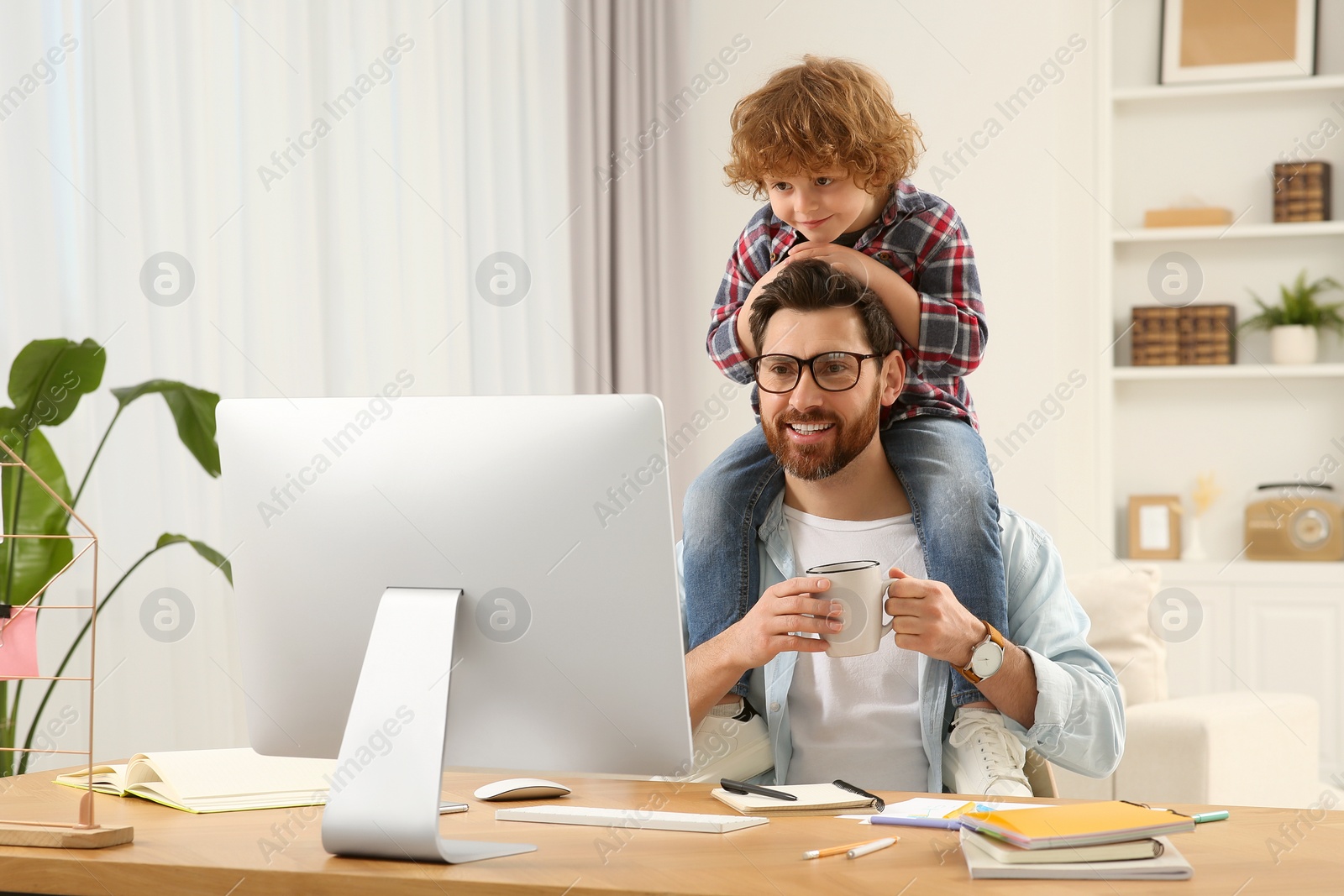 Photo of Man working remotely at home. Father with his child at desk