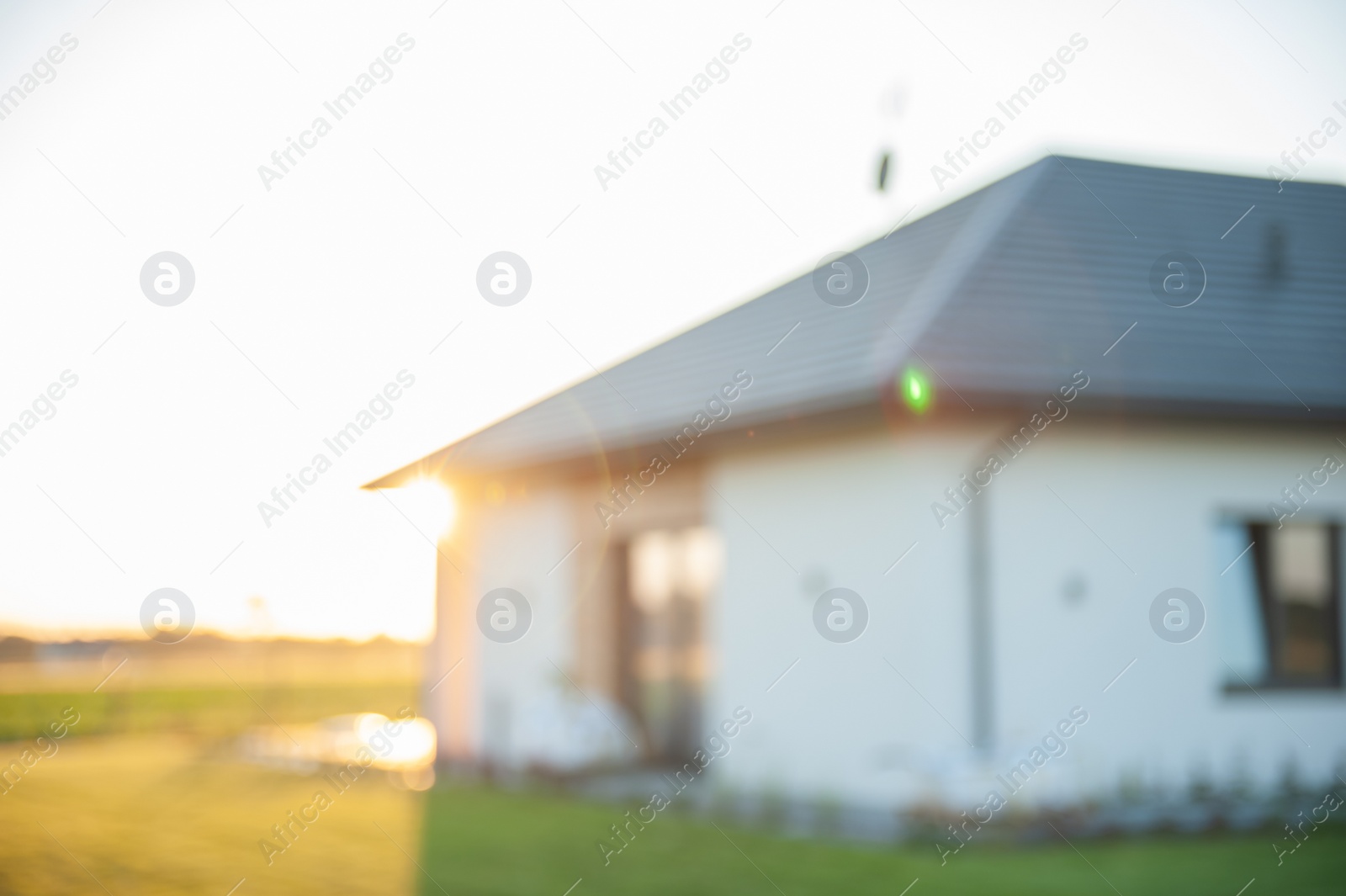 Photo of Blurred view of beautiful house with green lawn on sunny day