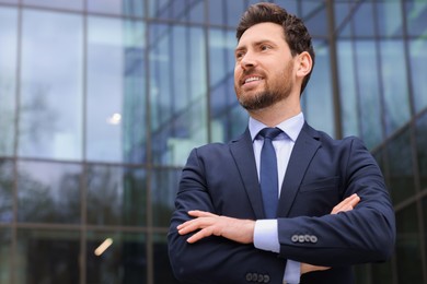 Happy real estate agent in suit outdoors. Space for text