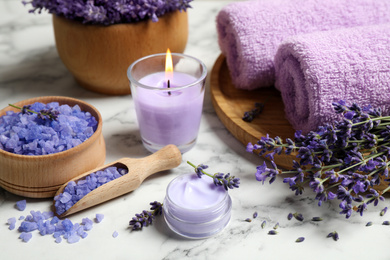 Cosmetic products and lavender flowers on white marble table