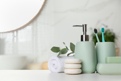 Image of Bath accessories. Different personal care products and eucalyptus leaves on white table in bathroom, space for text