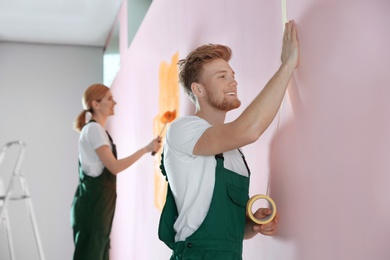 Photo of Professional decorators painting wall indoors. Home repair service