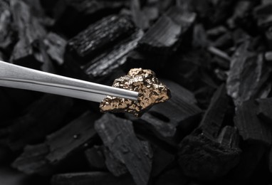 Tweezers with gold nugget above coals, closeup