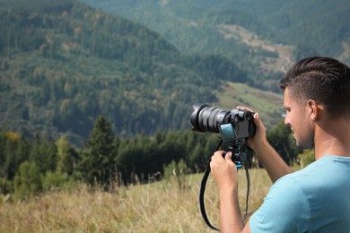 Photo of Professional photographer taking picture with modern camera in mountains. Space for text