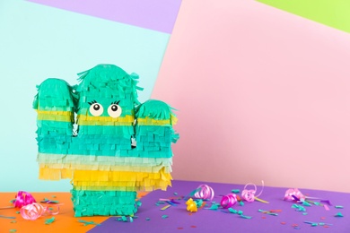 Photo of Cactus shaped pinata and decor on color background. Space for text