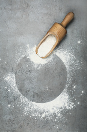 Photo of Flour and wooden scoop on light grey table, top view. Space for text