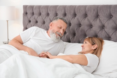 Mature couple together in bed at home