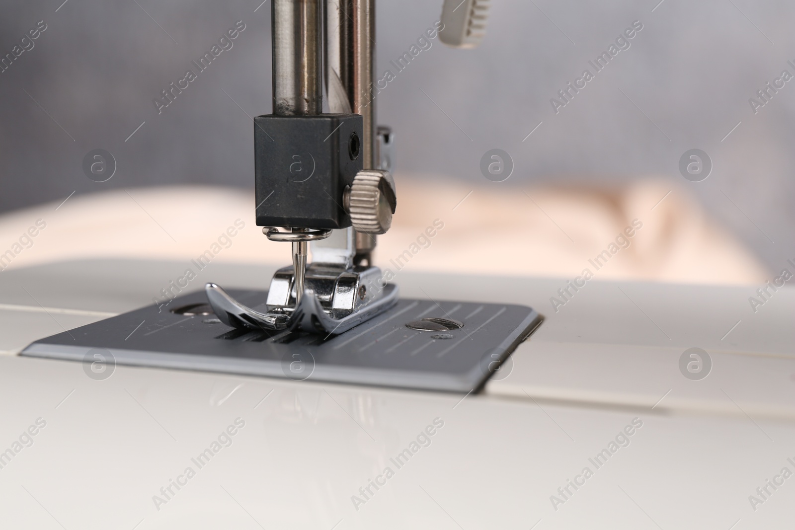 Photo of White sewing machine on blurred background, closeup