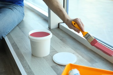 Image of Man painting window frame at home, closeup