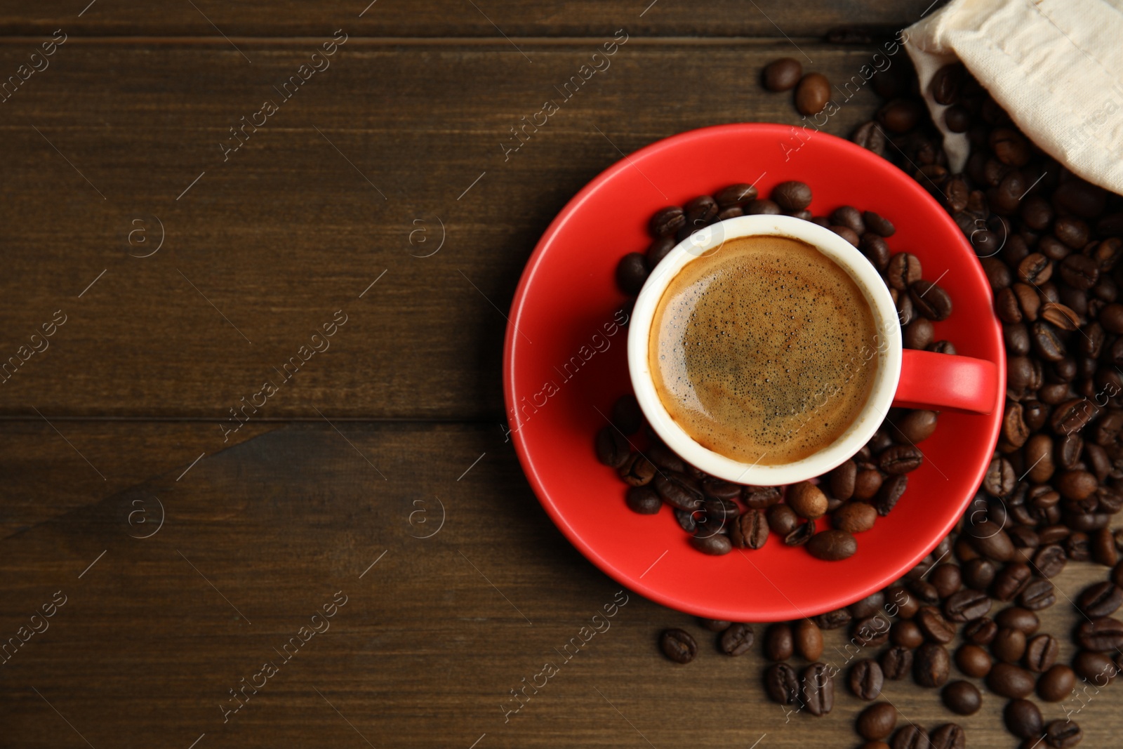 Photo of Cup of tasty coffee and beans on wooden table, flat lay. Space for text