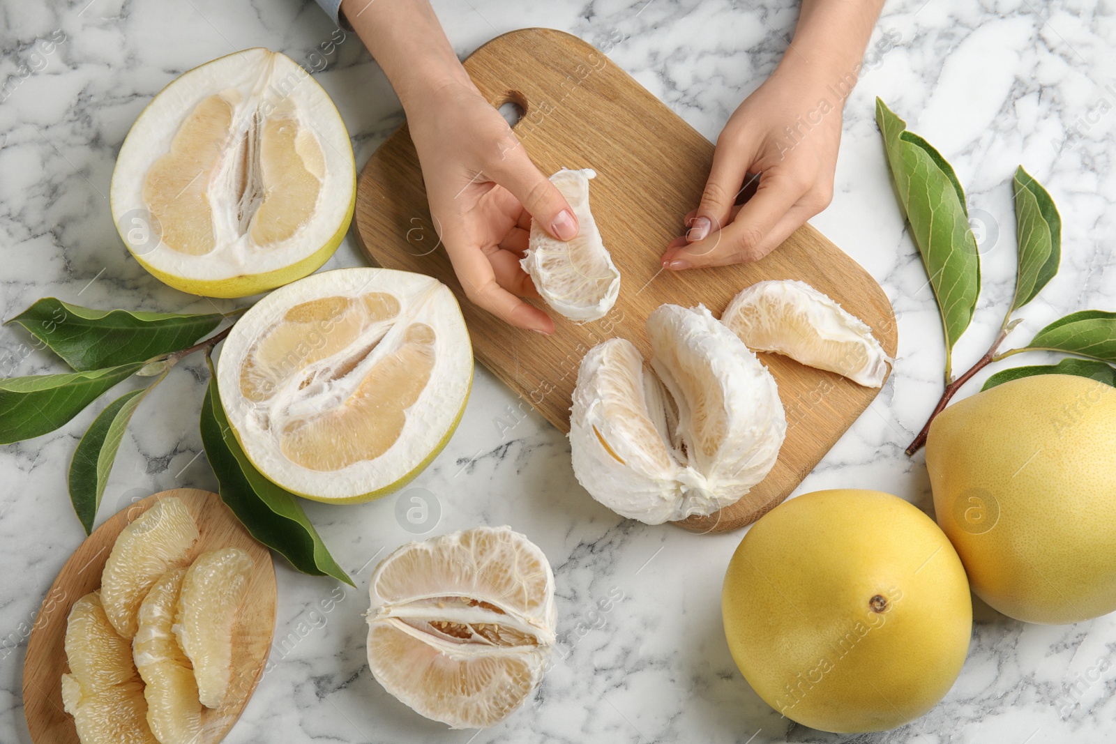 Photo of Woman with tasty ripe pomelo at white marble table, top view