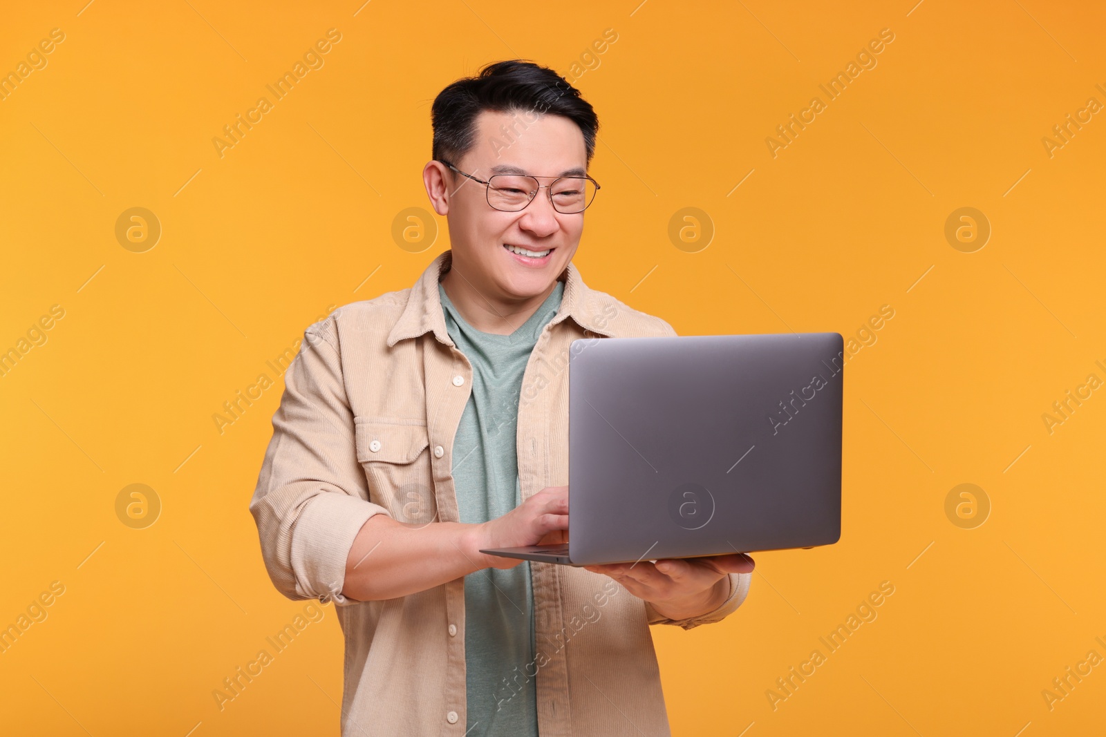 Photo of Happy man with laptop on yellow background