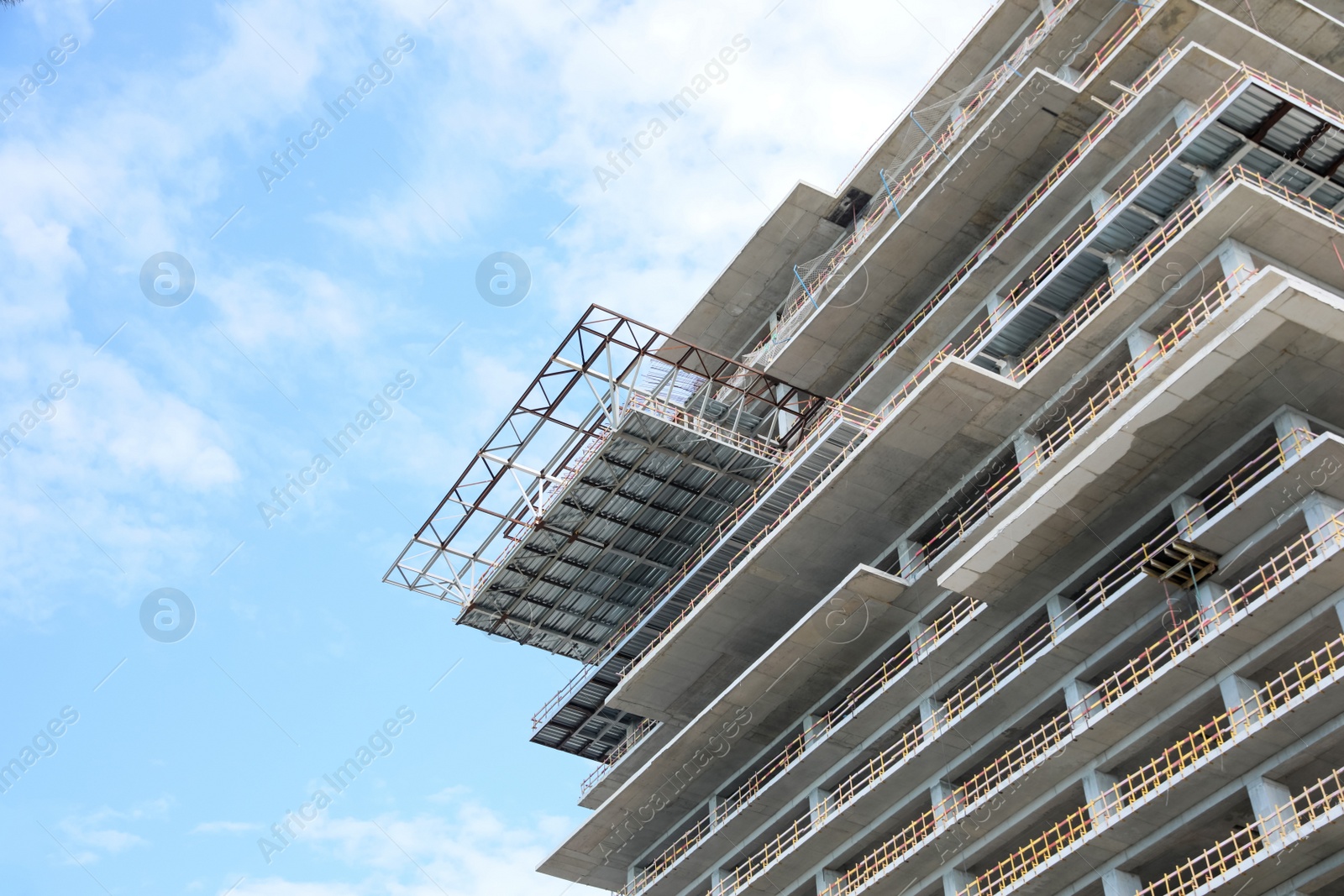 Photo of Multistory building under construction against cloudy sky, low angle view