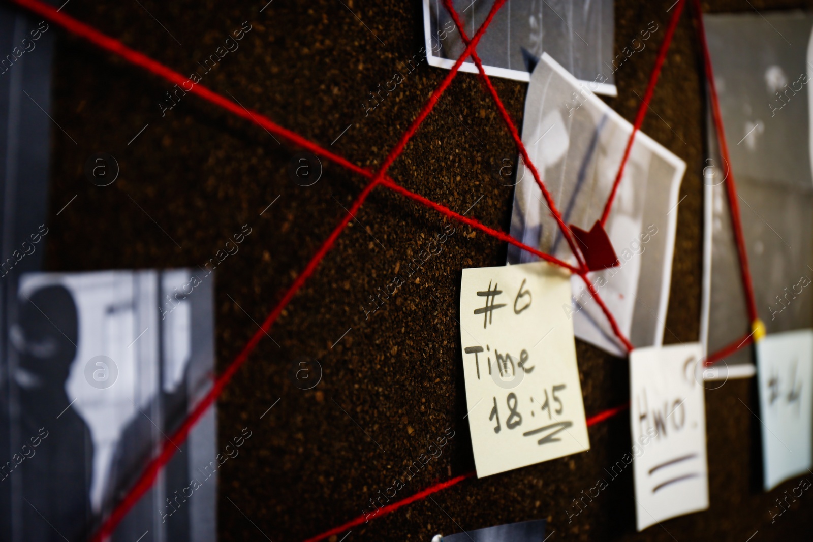 Photo of Detective board with crime scene photos, stickers, clues and red thread, closeup