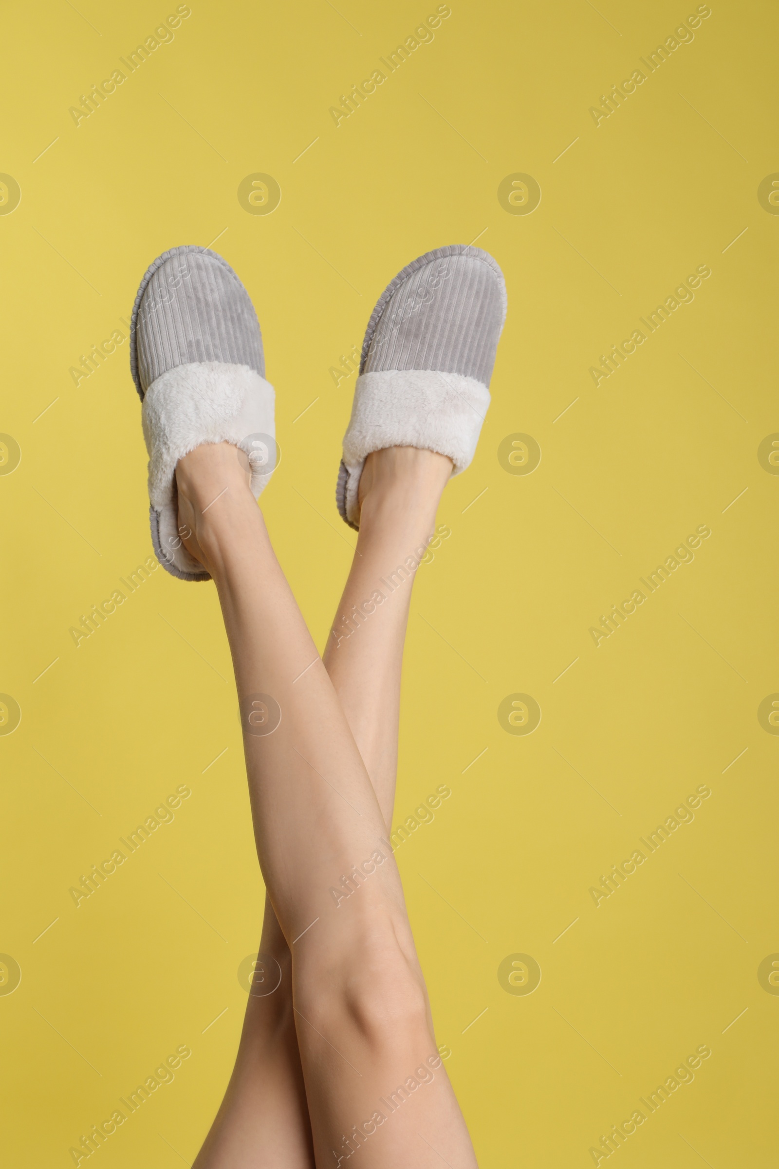 Photo of Woman wearing stylish slippers on yellow background, closeup