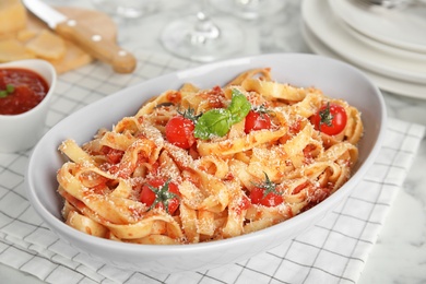 Photo of Tasty pasta with tomatoes, cheese and basil on table