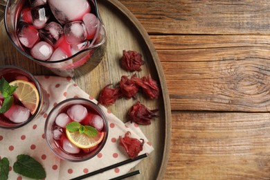 Delicious iced hibiscus tea, dry flowers and straws on wooden table, top view. Space for text