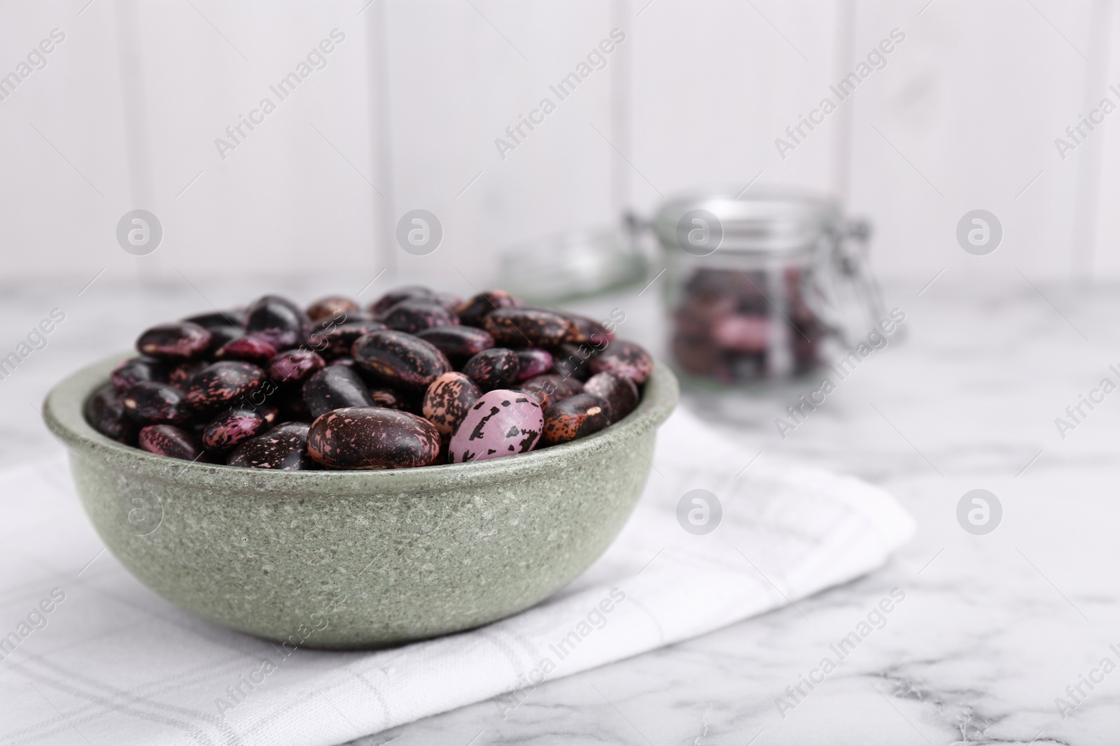 Photo of Bowl with dry kidney beans on white marble table. Space for text