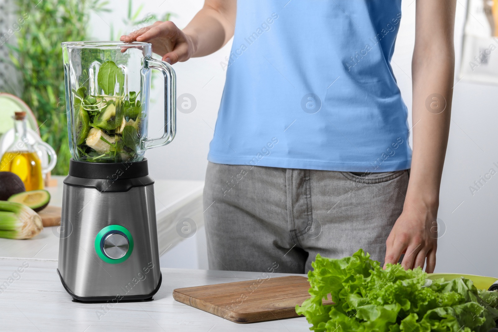 Photo of Woman preparing tasty green smoothie in kitchen, closeup