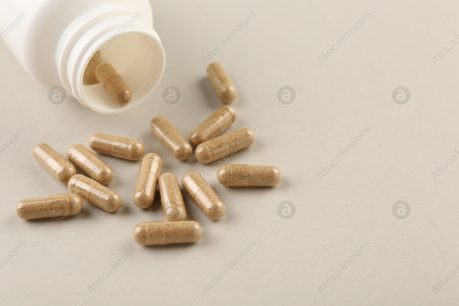 Photo of Bottle and vitamin capsules on light background, closeup. Space for text