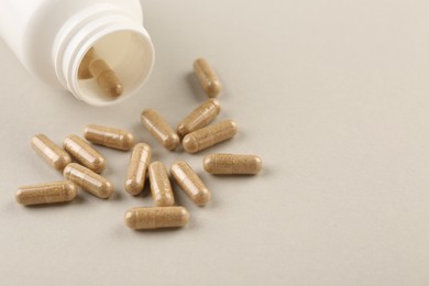 Bottle and vitamin capsules on light background, closeup. Space for text