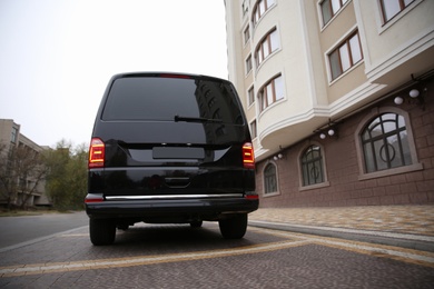 Black delivery van parked on street near building