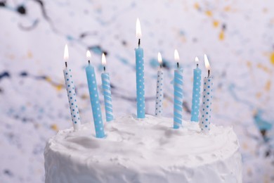 Delicious cake with cream and burning candles on color background, closeup