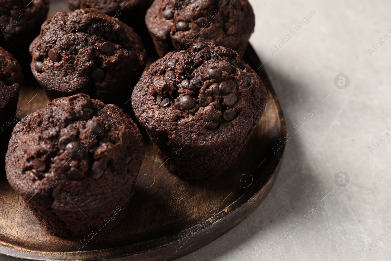 Photo of Board with delicious chocolate muffins on light table, closeup